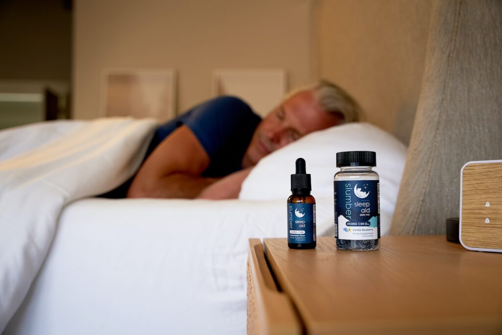 a man sleeping on a bed next to a bottle of cb