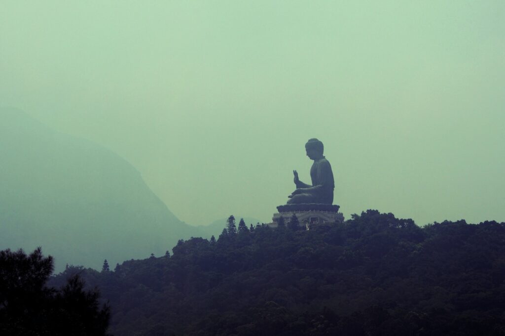 silhouette of man sitting on rock formation during foggy day